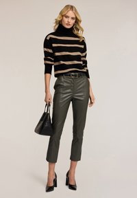 Černý a béžový pruhovaný pletený rolák, olivové kožené kalhoty, černá kabelka a černé lakované lodičky.