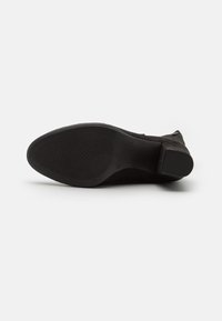 Stivale alla caviglia in suede nero con punta arrotondata e superficie liscia. Suola piatta in gomma con battistrada tassellato per una migliore aderenza.