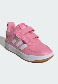 Różowy but sportowy z syntetyczną cholewką, dwoma paskami na rzep, białymi akcentami i gumową podeszwą. Posiada teksturowany obcas oraz wyściełany kołnierz.