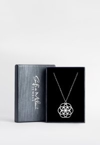 Silberner Anhänger mit einem filigranen Blumendesign, präsentiert in einem schwarzen Samtinneren einer metallic grauen Box.