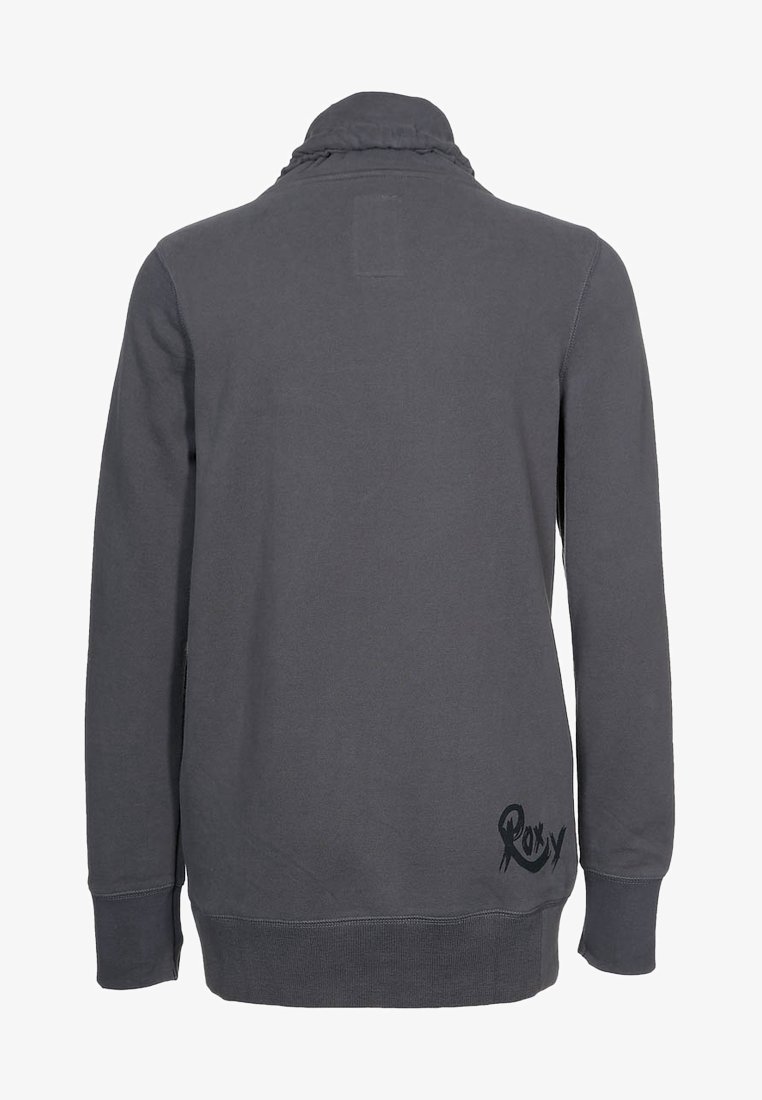 Sweat-shirt gris foncé à manches longues avec col haut, coutures visibles et logo "Roxy" près de l'ourlet bas arrière sur le côté droit.