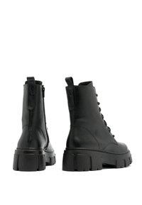 Botas de tobillo de cuero negro con suela gruesa, parte delantera con cordones y cremallera lateral. Acabado texturizado y tirador en la parte posterior para facilitar su uso.