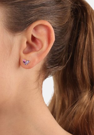 Silberne Schmetterlings-Stud-Ohrringe mit lila Emaille-Akzenten, markanten Flügelformen und einer polierten Oberfläche, getragen am Ohr eines Models.