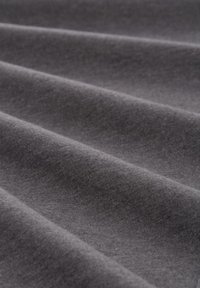 Tissu gris foncé drapé en plis doux et lisses, mettant en valeur une texture tricotée fine avec un léger éclat et une couleur uniforme tout au long.