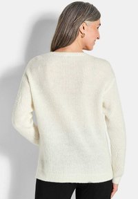 Cremfarbener, gestrickter Pullover mit lockerer Passform, der über eine gerippte Textur und lange Ärmel verfügt und ein schlichtes Design ohne Verzierungen zeigt.