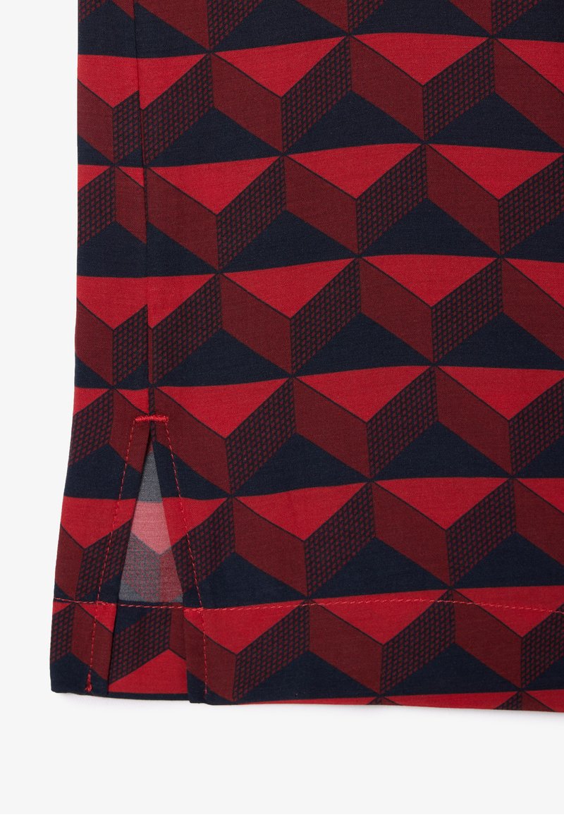 Baumwollstoff mit einem geometrischen Muster in Rot und Marineblau, das 3D-Würfelformen mit strukturierten Akzenten zeigt. Seitenschlitzdetails mit roter Nähte.