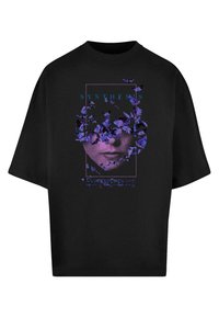 Sort oversized t-shirt med grafisk design af lilla sommerfugle og et ansigt, med teksten "SYNTHESIS" og "EVANESCENCE" i blåt.
