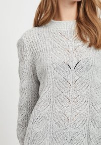 Lichtgrijze gebreide trui met een textuurpatroon van bladeren, geribbelde halslijn en lange mouwen, met open stiksels voor extra detail.