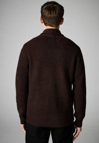 Mörkbrun stickad tröja med ett strukturerat mönster, ribbade ärmslut och nederkant, med en sjalkrage och rak kroppdesign.