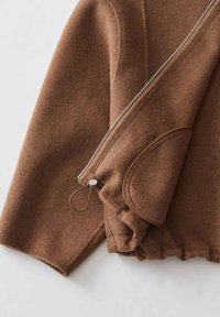Braune Wolljacke mit einem Ärmel, silbernem Reißverschluss, elastischem Bündchen und Klappentaschendetail auf weißem Hintergrund.