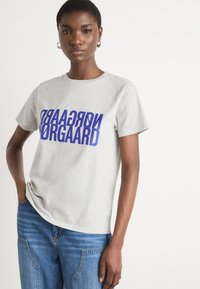 Gray cotton t-shirt with short sleeves, featuring bold blue printed text "NORGAARD" across the front, complementing straight blue jeans.