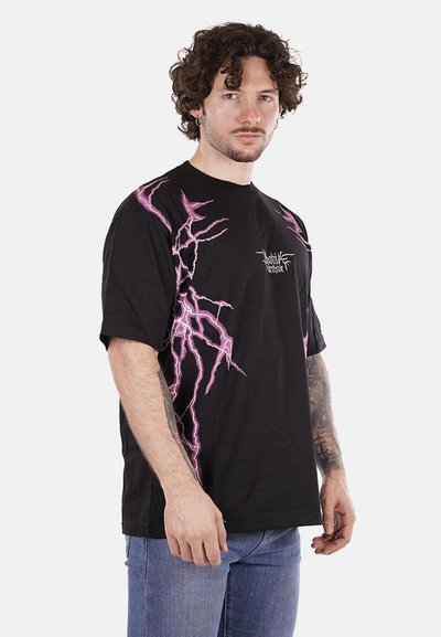 T-shirt nera in cotone con vestibilità oversize, caratterizzata da grafiche di fulmini rosa sui lati e un piccolo logo sul petto.
