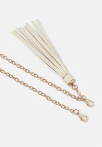 Kožený střapec v krémové barvě připevněný ke kovovému řetězu v zlaté barvě s kruhovými články a karabinkou pro bezpečné zapínání.