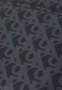 Țesătură texturată neagră cu un model de logo repetat. Designul are un luciu subtil și este realizat dintr-un material ușor și durabil.
