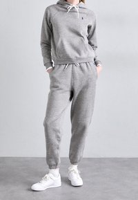 Grå bomullshoodie med kängurufickor, dragsko och ribbade muddar; ihopparad med matchande joggers med elastisk midja och muddar.