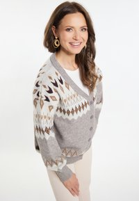 Cardigan grigio con motivi geometrici in beige, marrone e bianco, con scollatura a V profonda, maniche lunghe e cinque bottoni.