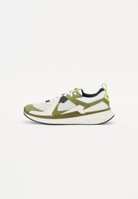 Sportliche Sneakers mit einem weißen Mesh-Obermaterial, olivgrünen Wildlederakzenten, schwarzen Details, strukturierten Sohlen und einer limettengrünen Fersenlasche.
