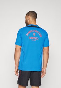 Karališkai mėlynas T365 marškinėlis su juodu akcentu ant apykaklės. Didesnis raudonas "Manchester United" logotipas puikuojasi per nugarą su užrašu "EST 1878".