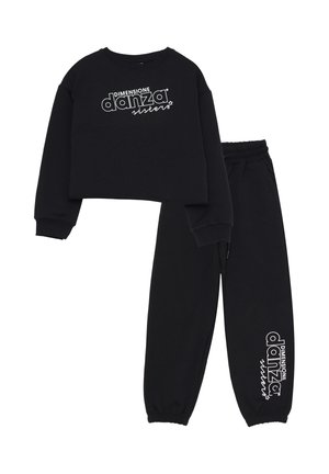 Felpa nera corta con testo bianco "DIMENSIONE danza sisters" e pantaloni felpati neri abbinati con lo stesso logo vicino alla caviglia.