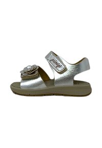 Sandali metallici argento con decorazione a fiore, cinturino in Velcro, design con punta aperta e suola texturizzata color tan per aderenza e comfort.