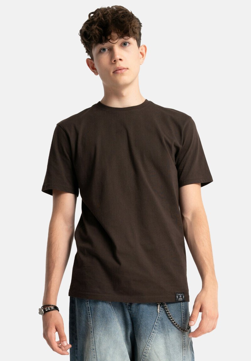 Brązowa bawełniana koszulka z krótkimi rękawami, okrągłym dekoltem i subtelną teksturą. Połączona z jasnymi dżinsami z akcentem w postaci łańcucha.