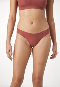 Rosa nylon truse med sømløse kanter, minimalistisk design og myk tekstur. Har lav midje og glatt overflate.