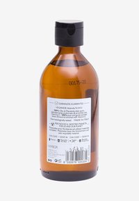 Klarglasflaska i amberfärg med svart kork, försedd med en etikett som innehåller produktinformation, inklusive ingredienser och certifieringsdetaljer.