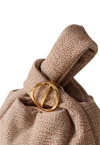 Sac à main beige texturé avec un design froncé, mettant en avant un accent en métal doré de forme circulaire et une finition en tissu lisse et doux.