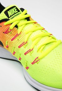 Tenisky Nike Zoom Pegasus 33 mají jasně žlutý síťovinový svršek s oranžovými a růžovými akcenty, ploché šňůrky a texturovanou podrážku.