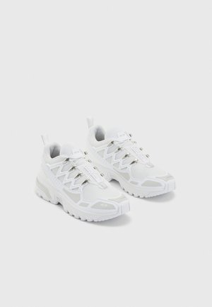 Weiße Sportschuhe mit einem Obermaterial aus Mesh, verstärkter Zehenpartie und einem markanten Schnürverschlussdesign. Dicke Gummisohle mit strukturiertem Profil.