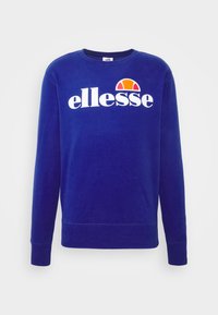Sweat-shirt bleu en tissu doux, avec un col rond et des manches longues. Affiche un logo "ellesse" blanc avec un demi-cercle orange et jaune.