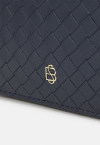 Portafoglio in pelle intrecciata blu navy con accento del logo dorato. Texture liscia con un motivo geometrico e bordi cuciti per una maggiore durata.