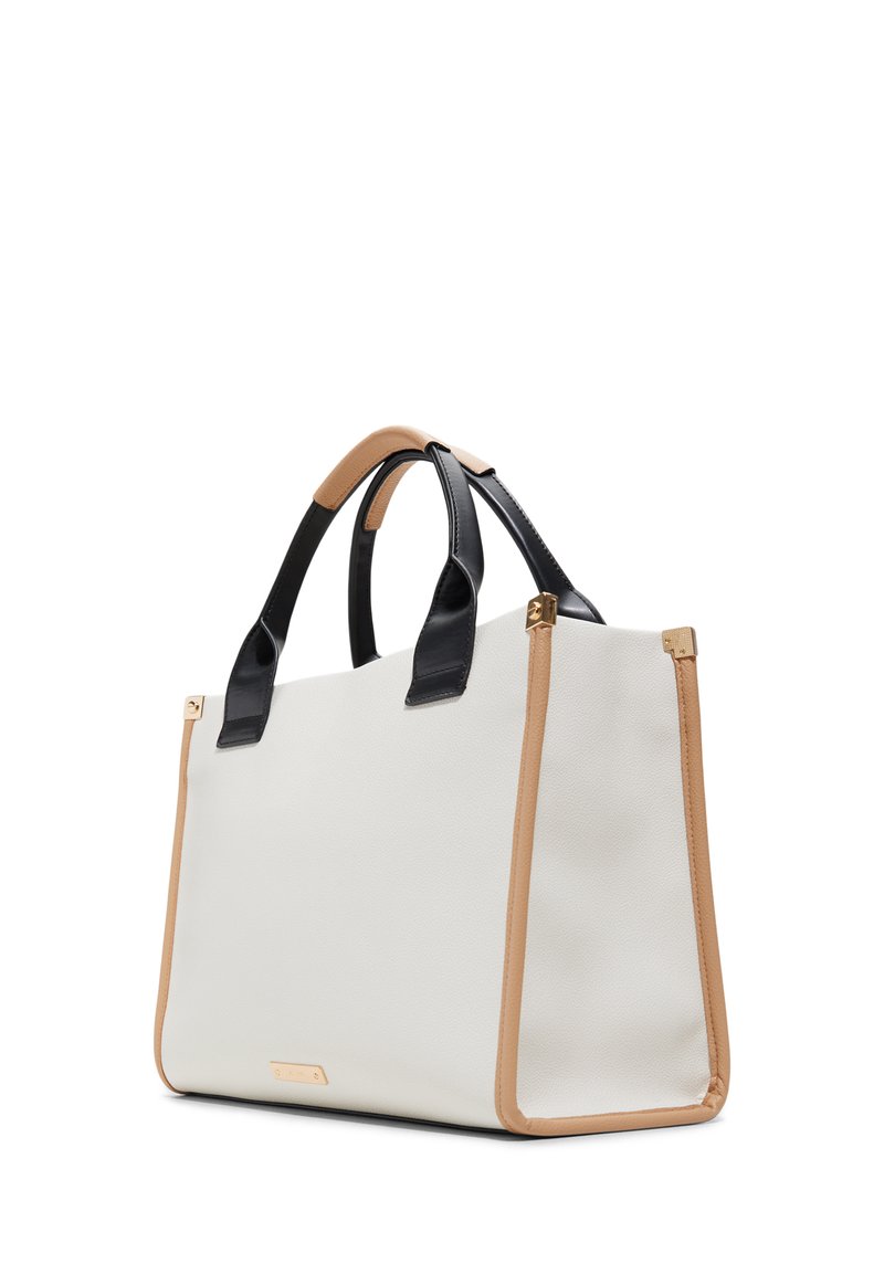 Sac fourre-tout texturé blanc avec des poignées en cuir noir et des accents beige. Équipé de matériel en métal doré à la base des poignées. Forme cubique.