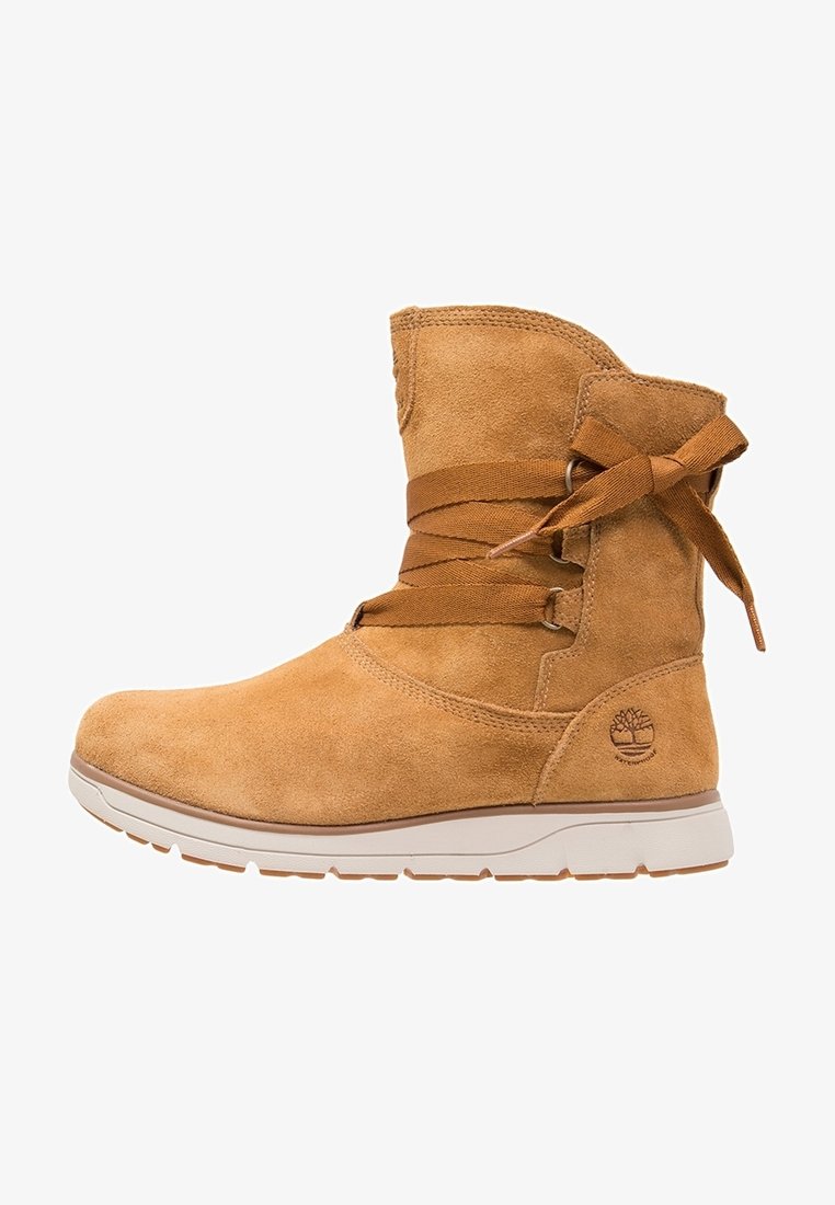 Suède enkellaars in tan, met een ronde neus, een vetersluiting met een lint en een witte rubberen loopzool. Logo-embleem aan de zijkant.