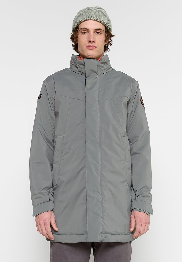 Giacca isolante grigia con colletto alto, zip frontale e due tasche laterali. Tessuto morbido, design a lunghezza media e patch con logo sulla manica sinistra.