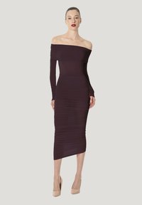 Off-shoulder, langærmet, mørkelilla kjole med rynket tekstur, tætsiddende silhuet og knælængde, kombineret med nude højhælede sko.