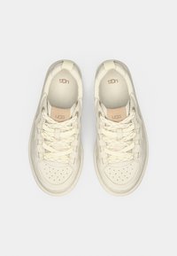 Baskets blanches en cuir lisse avec motif perforé, lacets plats et accents de logo subtils sur la languette, dotées d'une pointe arrondie.