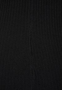 Tissu noir côtelé présentant une surface texturée avec des lignes verticales, affichant une finition lisse et un motif cohérent partout.