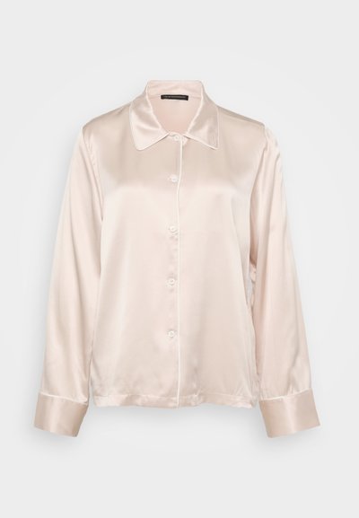 Satin skjorta med knappar i ljusrosa, med spetsig krage, långa ärmar och kontrasterande knappstängningar. Slät textur och manschettdetaljer.