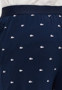 Marine katoen shorts met een herhalend wit krokodillenpatroon, een elastische tailleband en een gladde, zachte textuur.
