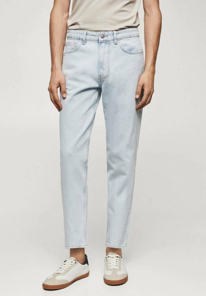 Světle modré džíny s rovnými nohavicemi, se zapínáním na knoflíky, pěti kapsami a decentními švy. Nalezeny s bílými teniskami.