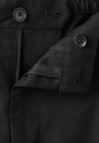 Schwarzes Kleidungsstück mit Reißverschluss, zwei Vierlochknöpfen, Knopflöchern und einer umgeschlagenen Lasche mit detaillierter Naht.