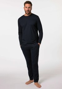 Maglietta a maniche lunghe color navy e pantaloni slim-fit abbinati, realizzati in materiale morbido con una texture liscia. I pantaloni presentano tasche frontali.