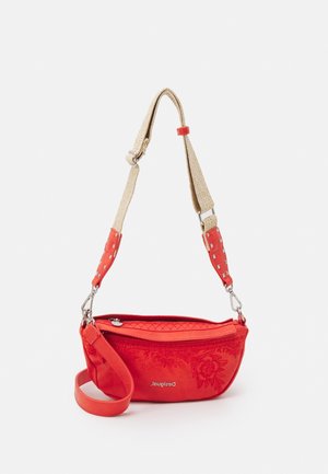 Červená kabelka přes rameno s květinovým vzorem, béžovým nastavitelným popruhem s hroty, zapínáním na zip a odnímatelným červeným náramkem na zápěstí.