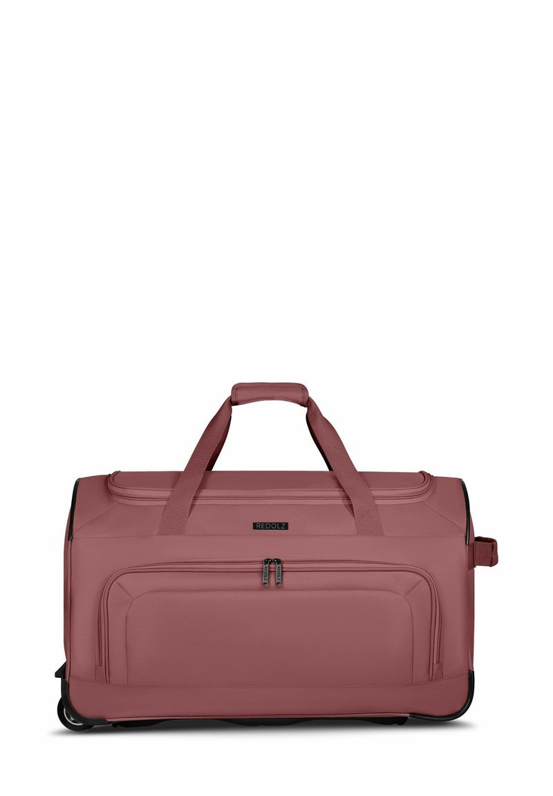 Grand sac de sport en tissu rose doux avec deux poignées supérieures, une poche frontale zippée et des accents noirs sur le bas et les fermetures éclair.