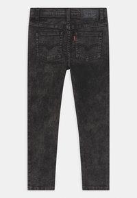 Vaqueros ajustados de lavado oscuro hechos de denim, con un diseño clásico de cinco bolsillos, textura sutilmente desgastada y una etiqueta con la marca en la parte trasera.