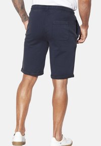 Navy cotton shorts with an elastic waistband, rolled cuffs, and a rear pocket. Smooth texture with minimal stitching details.