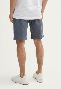Donkerblauwe korte broek met een patroon, gemaakt van lichtgewicht stof, met een comfortabele pasvorm en omgeslagen zoom, gecombineerd met witte sneakers.