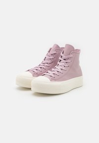 Para jasnofioletowych wysokich trampków z białą gumową podeszwą i sznurówkami, prezentowanych na jednolitym białym tle.