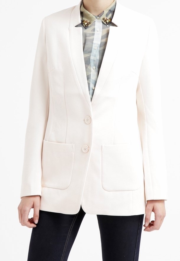 White tailored blazer with two front pockets and two buttons, worn over a camouflage-patterned shirt. Smooth texture, structured design.